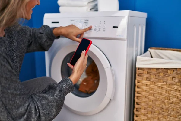 Çamaşır Odasında Çamaşır Makinesi Bekleyen Akıllı Telefon Kullanan Genç Sarışın — Stok fotoğraf