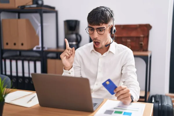 若いヒスパニック系の男は コンピュータのノートパソコンを使用して働いている側に指を指して驚いてクレジットカードを保持し 口を開けて驚くような式 — ストック写真