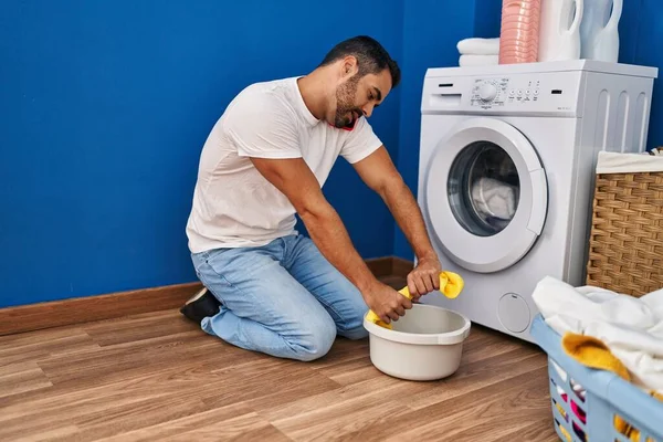 Young Hispanic Man Talking Smartphone Wringing Out Rag Laundry Room — ストック写真