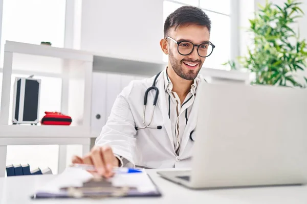 Young Hispanic Man Doctor Smiling Confident Using Laptop Clinic — Zdjęcie stockowe