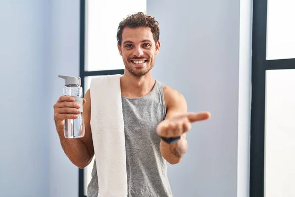 Jonge Spaanse Man Draagt Sportkleding Drinkwater Glimlachend Vrolijk Aanbieden Palm — Stockfoto