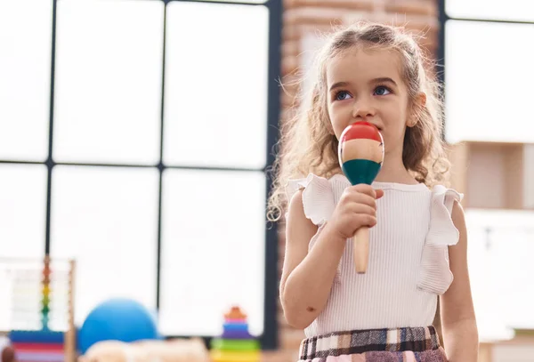 Stock image Adorable caucasian girl singing song using maraca as a microphone at classroom