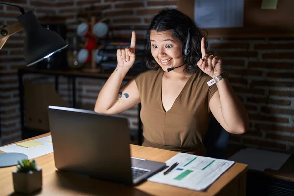 Young Hispanic Woman Working Office Night Smiling Amazed Surprised Pointing —  Fotos de Stock