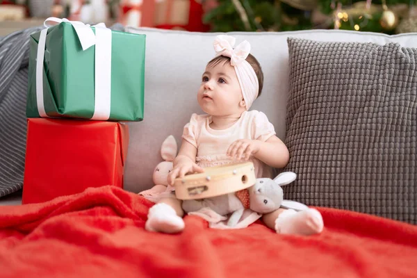 愛らしい幼児遊びタンバリン座っています上のソファによってクリスマスツリーホーム — ストック写真