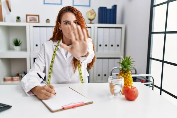 Young Redhead Woman Nutritionist Doctor Clinic Doing Stop Sing Palm — Stock Photo, Image