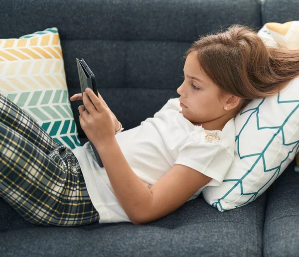 Adorable Hispanic Girl Using Touchpad Lying Sofa Home — Stok fotoğraf