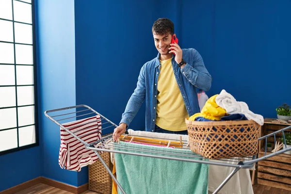Ung Latinamerikan Man Talar Smartphone Hängande Kläder Klädstreck Tvättstuga — Stockfoto