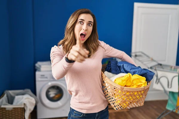 Young Woman Holding Laundry Basket Pointing Finger Surprised Ahead Open — Stock Photo, Image
