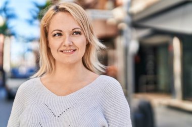 Young blonde woman smiling confident looking to the side at street