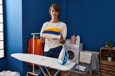 Brunette woman holding folded laundry after ironing skeptic and nervous, frowning upset because of problem. negative person. 