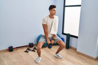 Genç İspanyol adam spor merkezinde kettlebell kullanıyor.