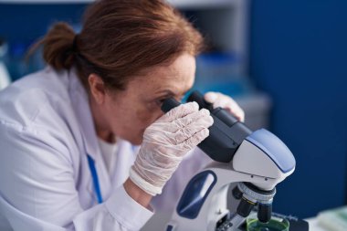 Senior woman scientist using microscope at laboratory