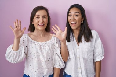 İspanyol anne ve kızı birlikte on numarayı gösterip işaret ederken kendinden emin ve mutlu gülümsüyorlar.. 