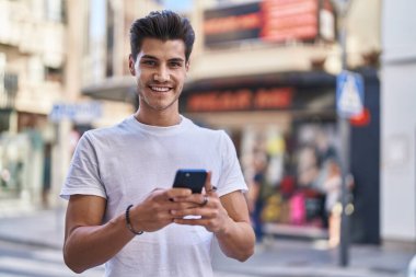 Sokakta akıllı telefon kullanan, kendine güvenen genç bir İspanyol.