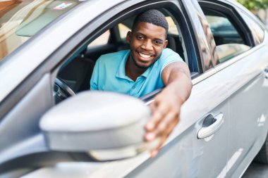 Young african american man smiling confident touching car rear view at street