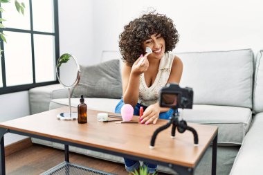 Orta Doğulu genç bir kadın gülümsüyor. Evde kendine güvenen makyaj dersi veriyor.