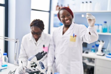 African american women scientists looking sample writing on document at laboratory