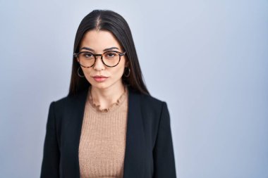 Mavi arka planda duran genç esmer kadın üzgün ve endişeli, sinirli ve korkmuş bir şekilde ağlıyor. hüzünlü ifade. 