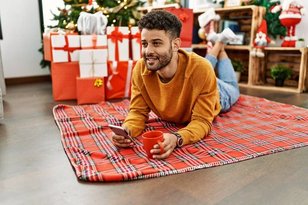 Young Arab Man Using Smartphone Drinking Coffee Lying Floor Christmas — Stock Photo, Image