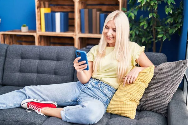 Junge Blonde Frau Sitzt Mit Smartphone Hause Auf Sofa — Stockfoto