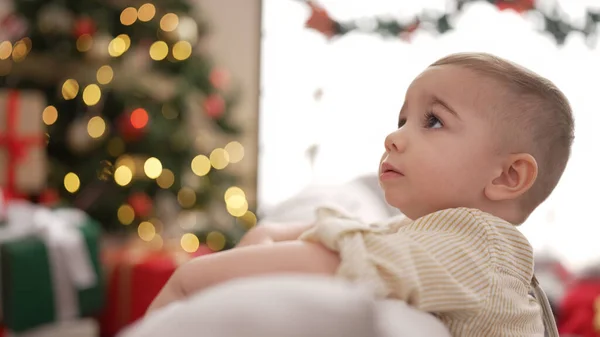 可爱的幼儿坐在圣诞树旁的沙发上 脸上带着严肃的表情 — 图库照片