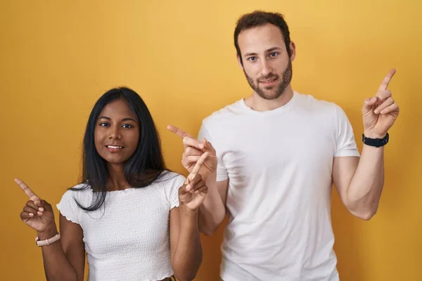 Interracial Couple Standing Yellow Background Smiling Confident Pointing Fingers Different — Foto Stock