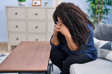 Afrikalı Amerikalı kadın evdeki kanepede otururken strese girdi.