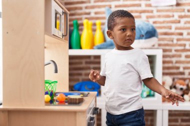 Afrika kökenli Amerikalı çocuk anaokulunda mutfakta oyun oynuyor.