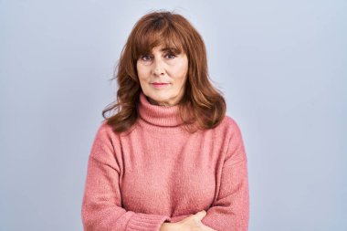 Middle age hispanic woman standing over isolated background relaxed with serious expression on face. simple and natural looking at the camera. 