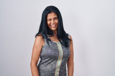 Beyaz arka plan üzerinde duran olgun İspanyol kadın kameraya seksi bir ifadeyle bakıyor, neşeli ve mutlu bir yüzle.. 