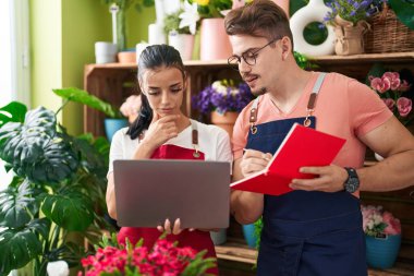 Çiçekçide dizüstü bilgisayar kullanan erkek ve kadın çiçekçiler.