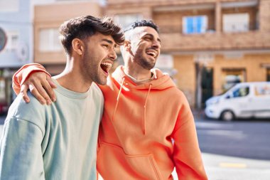 İki erkek caddede birbirlerine sarılıyorlar.