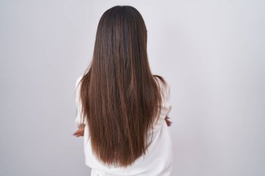 Young brunette woman wearing glasses standing backwards looking away with crossed arms 