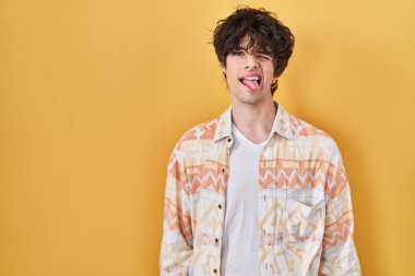 Young man wearing casual summer shirt sticking tongue out happy with funny expression. emotion concept. 
