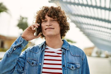 Genç İspanyol adam şehirde telefonla konuşuyor.