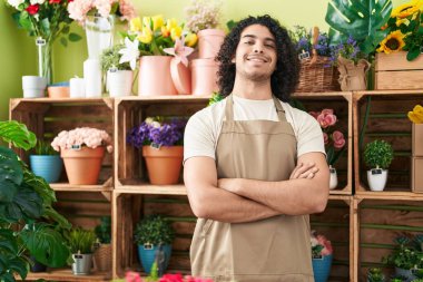 Çiçekçide kollarını kavuşturup duran kendine güvenen genç latin çiçekçi.