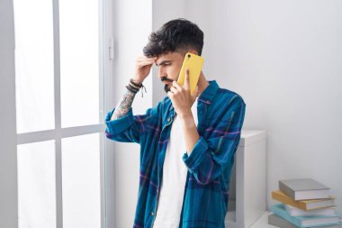 Genç İspanyol adam evde akıllı telefondan konuşmaktan endişeleniyor.