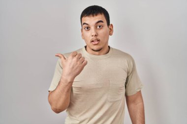 Gündelik tişört giyen genç bir Arap, elleri yana dönük, ağzı açık, şaşkın bir ifadeyle şaşırdı.. 