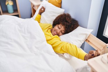 Afrikalı Amerikalı bir kadın yatak odasında kollarını açarak uyanıyor.