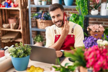 Çiçekçide dizüstü bilgisayar kullanarak konuşan İspanyol bir çiçekçi.