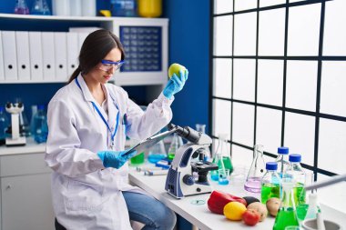 Genç ve güzel İspanyol bilim kadını. Laboratuvarda elma okuma belgesi tutuyor.