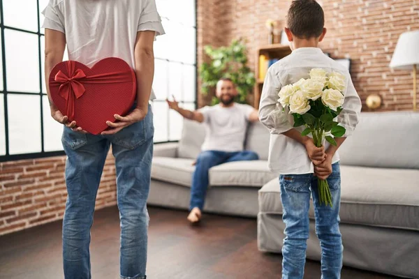 Family surprise father with gift and flowers on back at home