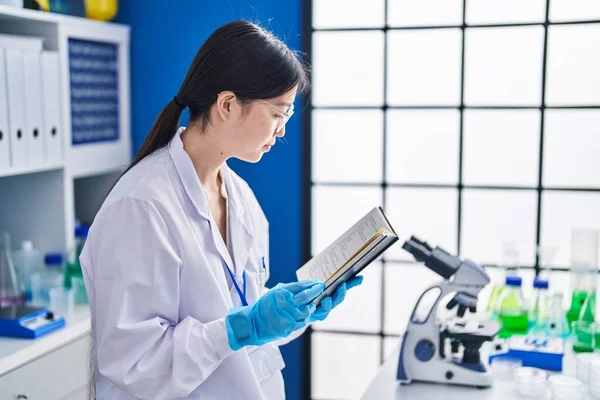 Chinese woman scientist reading book at laboratory