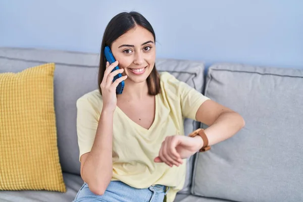 Young Hispanic Woman Talking Smartphone Looking Watch Home — Stockfoto