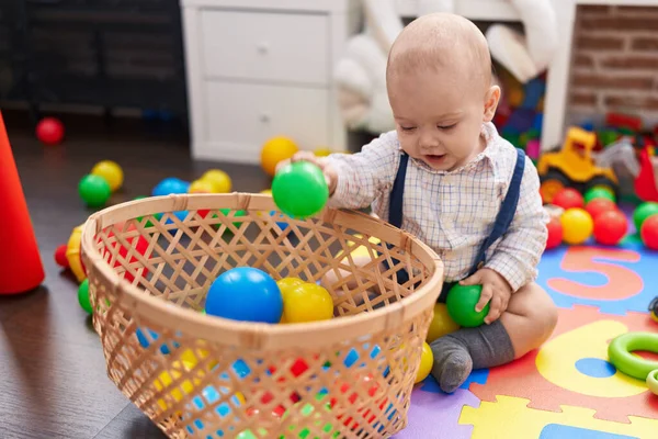 愛らしい白人の赤ちゃんは笑顔で自信を持って遊んでいますボールが幼稚園で床に座って — ストック写真