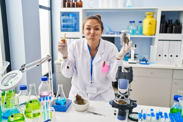 Young Hispanic Woman Doing Weed Oil Extraction Laboratory Puffing Cheeks — Stockfoto
