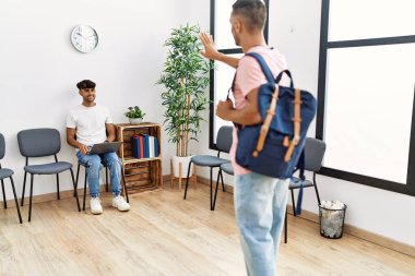 İki İspanyol adam bekleme odasında laptoplarını kullanıyor.