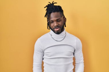 Sarı arka plan üzerine balıkçı yaka kazak giyen Afrikalı bir adam depresif ve endişeli, sinirli ve korkmuş. hüzünlü ifade. 