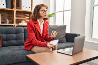 Beyaz kadın psikolog psikoloji merkezinde online danışmanlık yapıyor.