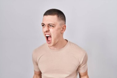 İzole edilmiş arka planda duran genç adam öfkeli ve öfkeli çığlıklar atıyor öfkeyle bağırıyor. öfke ve agresif konsept. 